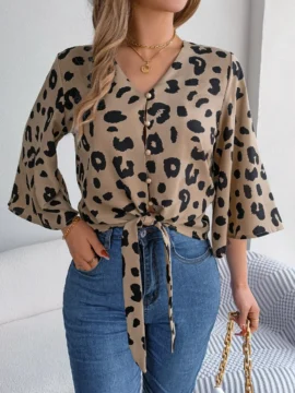 Front view of a woman wearing a brown and black Leopard Print Tie Front V-Neck Blouse tied at the waist with blue jeans